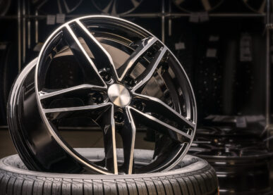 new expensive cast aluminum disc wheel black color, photographed on the tire. dark background, close-up